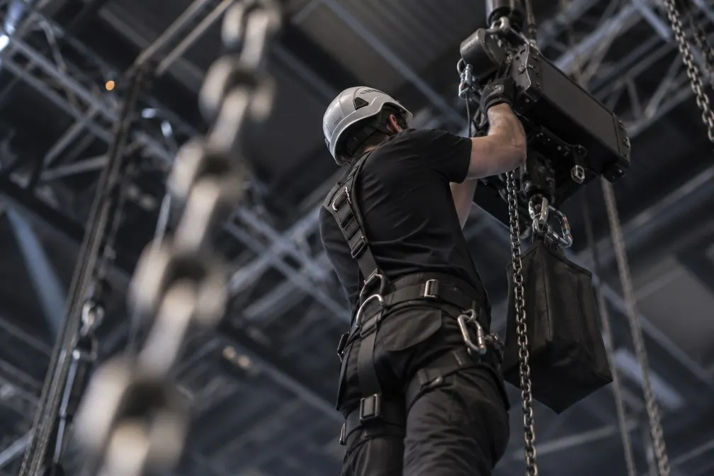 Rigger in harness installing a chain motor on overhead truss at a Las Vegas venue