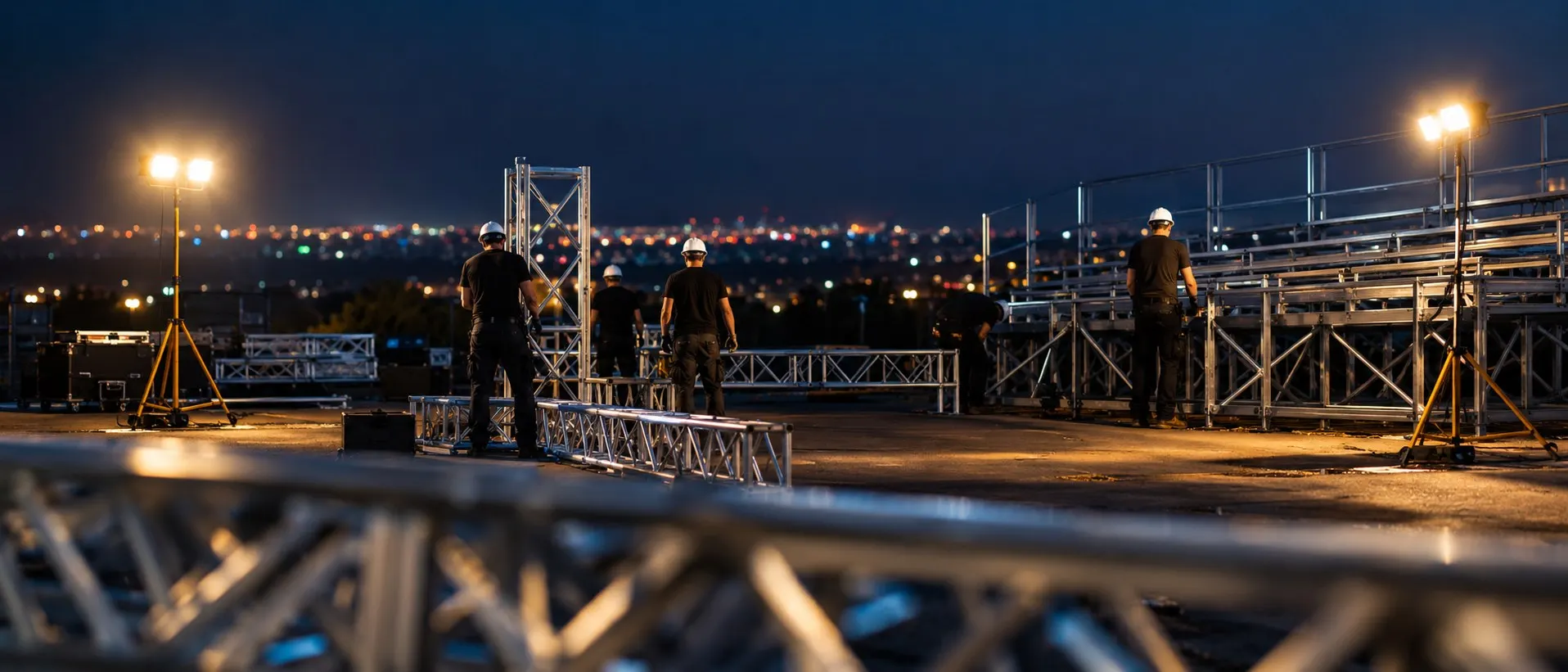 Expert Staging Productions crew installing grandstand and truss structure at night under work lights during Las Vegas race week