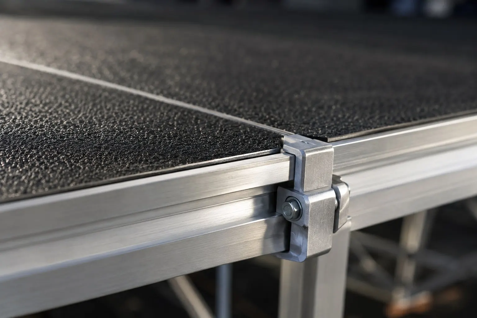 Close-up of modular aluminum stage decking and coupling clamp used on Expert Staging Productions stage builds